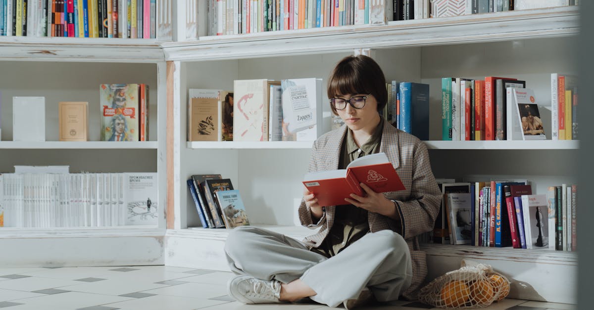 A young woman reading a red book in a library corner, surrounded by shelves with a variety of books.